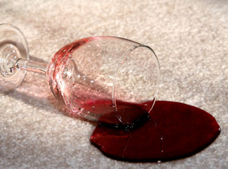 glass of wine knocked over with spilled wine on carpet